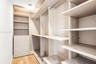 Walk-in closet featuring custom built-in cabinetry, integrated shelving, multi-level hanging rods, a four-drawer dresser unit, and wood-finish floorin
