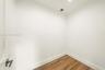 Interior space featuring white walls and wood-finish flooring with a modern square-profile door handle