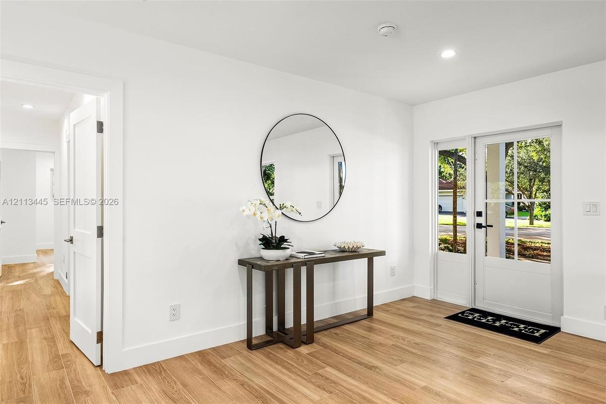 Entryway featuring light wood-finish flooring, recessed lighting, and a white exterior door with glass panels and a sidelight