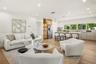 Open-concept kitchen featuring an expansive center island, integrated cabinetry, stainless steel appliances, and wood-finish flooring illuminated by r