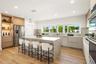 Kitchen featuring flat-panel cabinetry, a central island with a stone-finish countertop, wood-finish flooring, recessed lighting, and stainless steel 
