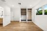 Built-in wardrobe featuring integrated shelving, pull-out drawers, and hanging rods, complemented by wood-finish flooring and recessed lighting