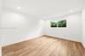 Bright room featuring wood-finish flooring, crisp white wall finishes, recessed lighting, and a window with exterior greenery