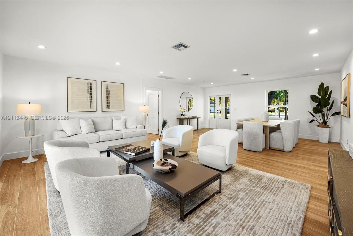 Open-concept interior featuring light-tone wood-finish flooring, recessed lighting, and crisp white walls