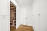 Walk-in closet featuring custom shelving and pull-out drawers, complemented by floor-to-ceiling built-in cabinetry, white shaker-style doors, and wood