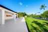 Covered concrete patio featuring white support columns, inground pool, manicured lawn, and perimeter fencing