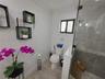 Bathroom featuring wood-finish flooring, a glass-enclosed shower with large-format tile walls, mosaic tile accent border, and built-in wall shelving