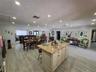 Kitchen featuring an expansive stone-topped island with shaker-style cabinetry, recessed ceiling lighting, and wood-finish flooring throughout