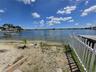 Waterfront parcel featuring a sandy shoreline, private wooden dock, and white picket fencing