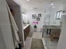 Bathroom featuring a wood-finish vanity with a light-toned countertop, walk-in glass-enclosed shower with tile surround, mosaic floor tiling, and wood