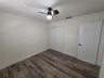 Wood-finish flooring, six-panel interior door with matte black hardware, sliding closet doors, and ceiling fan with integrated lighting