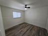 Interior room featuring wood-finish flooring, a neutral wall palette, a single window with horizontal blinds, and a ceiling-mounted fan with light fix