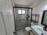 Walk-in shower featuring a sliding glass enclosure with a black frame, tiled wall surround, and pebble-finish shower floor