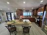 Kitchen featuring stained wood cabinetry, stone countertops, a central island with integrated seating space, recessed lighting, and stainless steel ap