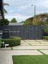 Private driveway featuring concrete pavers with artificial turf inlay, enclosed by a charcoal-finished privacy gate and manicured perimeter hedges