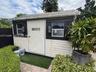 Detached structure featuring horizontal siding, dual windows with black trim, and wall-mounted exterior lighting
