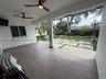 Covered patio featuring wood-finish flooring, recessed ceiling fans, and a large-format paver hardscape with grass inlays