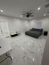 Large-format tile flooring with a veined pattern, recessed ceiling lighting, and a central ceiling fan