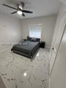 Large-format stone-style tile flooring, ceiling fan with integrated lighting, and window with built-in blind