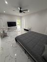 Large-format tile flooring with marble-style veining, recessed lighting, and a modern ceiling fan