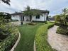 Landscaped exterior grounds featuring a paved walkway, manicured hedging, synthetic turf, and hardscaped patio area