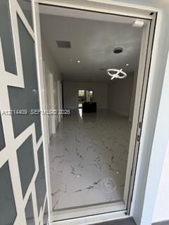 Entryway featuring a glass door with a geometric overlay, large-format tile flooring with veining detail, recessed ceiling lighting, and a modern scul
