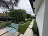 Landscaped side yard featuring manicured hedges, synthetic turf, stone-finish pavers, and an integrated post light