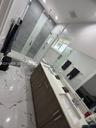 Dual-sink vanity with wood-finish cabinetry, white countertop, and integrated sinks, complemented by floor-to-ceiling tile in the walk-in glass-enclos