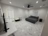 Spacious room featuring light-toned large-format tile flooring with veining, recessed lighting, a modern ceiling fan, and paneled doors