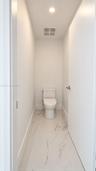 Minimalist water closet featuring large-format porcelain tile flooring with marble-style veining, a high-efficiency toilet, and recessed lighting