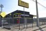 Commercial property featuring a concrete masonry structure, metal-slat security fencing, and an integrated overhead roll-up door