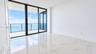 Floor-to-ceiling sliding glass doors, oversized tile flooring, and a glass-paneled balcony