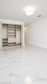 Large-format white tile flooring with veining, built-in closet organization system with integrated drawers and shelving, and flush-mount drum ceiling 