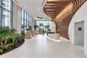 Lobby featuring large-scale floor-to-ceiling windows, parametric wood-slat ceiling detailing, stone-clad walls, large-format tile flooring, and integr