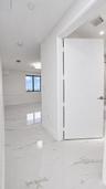 Large-format stone-finish tile flooring, minimalist solid-core interior door, and recessed lighting