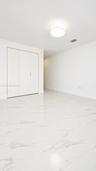 Polished stone-finish tile flooring, white walls, built-in closet with multi-panel doors, and a neutral drum-style ceiling fixture