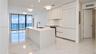 Modern kitchen featuring white flat-panel cabinetry, integrated appliances, a central island with a quartz countertop, and large-format porcelain tile