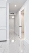Polished stone-finish flooring with marbled detailing, full-height built-in cabinetry, recessed ceiling lighting, and solid-core interior doors with m