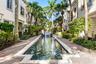 Elongated water feature with tiered fountain, surrounded by mature palm trees and lush landscaping
