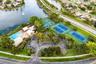 Recreational facility featuring a swimming pool, multiple tennis courts, a basketball court, and paved parking area situated on a waterfront lot