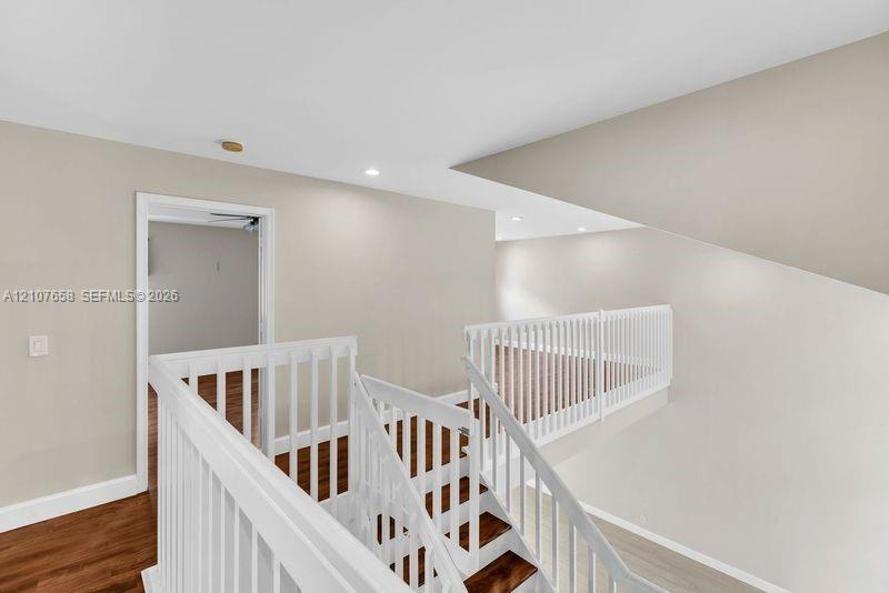 Open landing featuring wood-finish flooring, white spindle railings, and recessed ceiling lighting