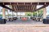 Covered pavilion featuring a vaulted timber-beam ceiling, exposed rafters, brick masonry grill island, and paver flooring