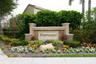 Community monument sign featuring stone veneer accents, stucco columns, and professionally landscaped flower beds