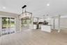 Kitchen featuring a central island, white cabinetry, a tiled backsplash, wood-finish flooring, and a large metal-frame chandelier