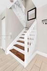Staircase featuring white balusters and railings with dark wood-finish treads, complemented by light wood-finish flooring