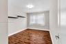 Interior room featuring wood-finish flooring, neutral wall tones, dual built-in wall shelves, and a flush-mount ceiling light fixture