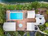Aerial perspective of community facilities featuring a rectangular swimming pool, a circular spa, brick-paver decking, and pitched-roof structures