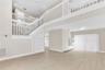 Two-story foyer with a mezzanine balcony, wood-finish flooring, white staircase featuring open shelving, and a wall-mounted floating storage unit