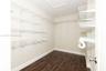 Walk-in storage space featuring wood-finish flooring and tiered white wire shelving units