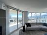 Floor-to-ceiling windows, sliding glass door, private balcony, and light-tone stone flooring